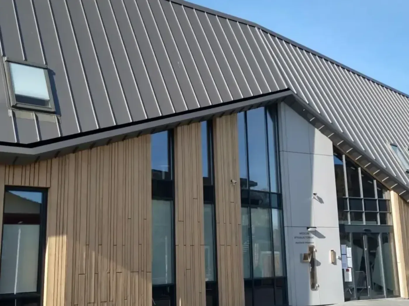 Klikfels-dak met dakramen boven een verticale houten gevelbekleding