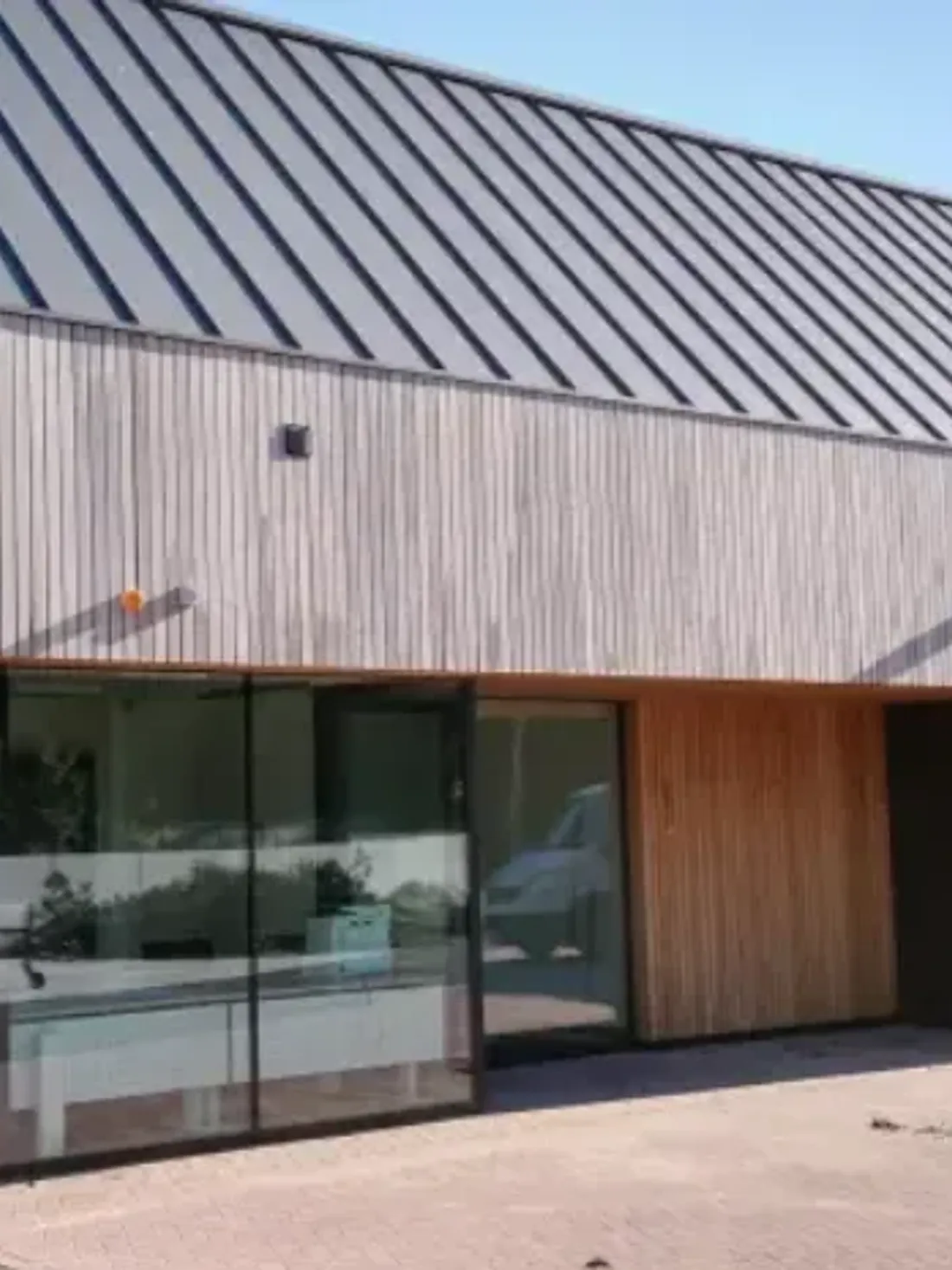 Klikfels op een bedrijfsgebouw, naast een lichte houten gevel