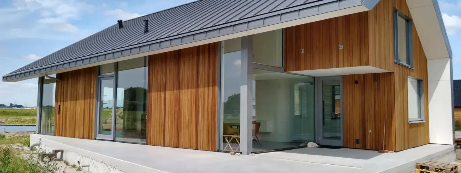 Woonhuis met houten gevelbekleding en een dak van KlikZink in donkere staande fels
